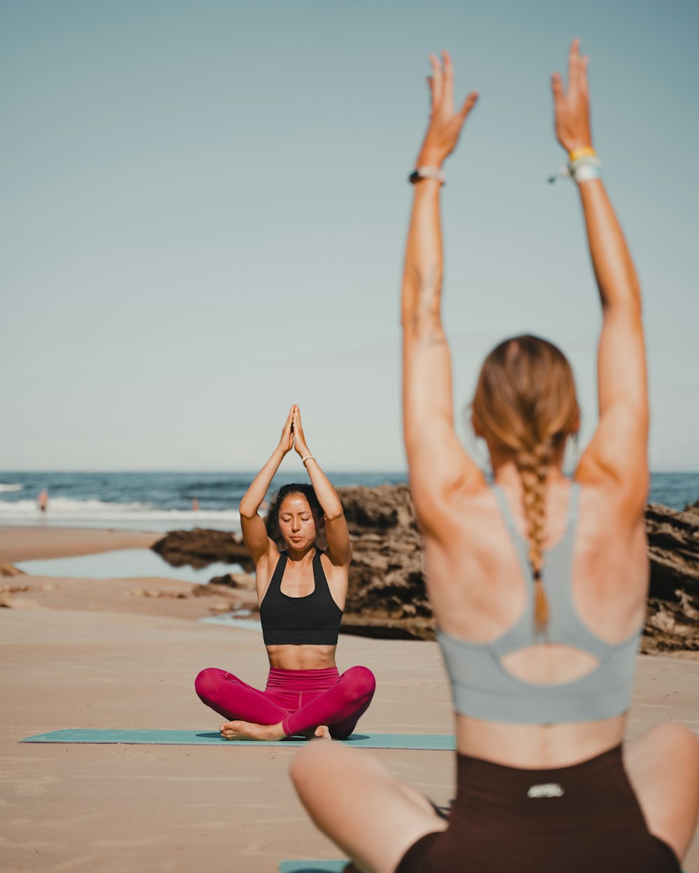 two women are doing yoga on the beach