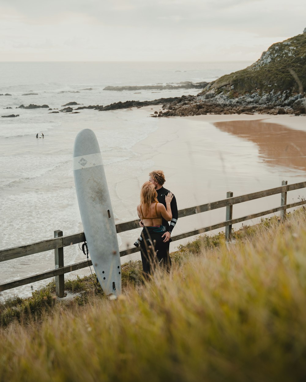 un homme et une femme debout à côté d’une planche de surf