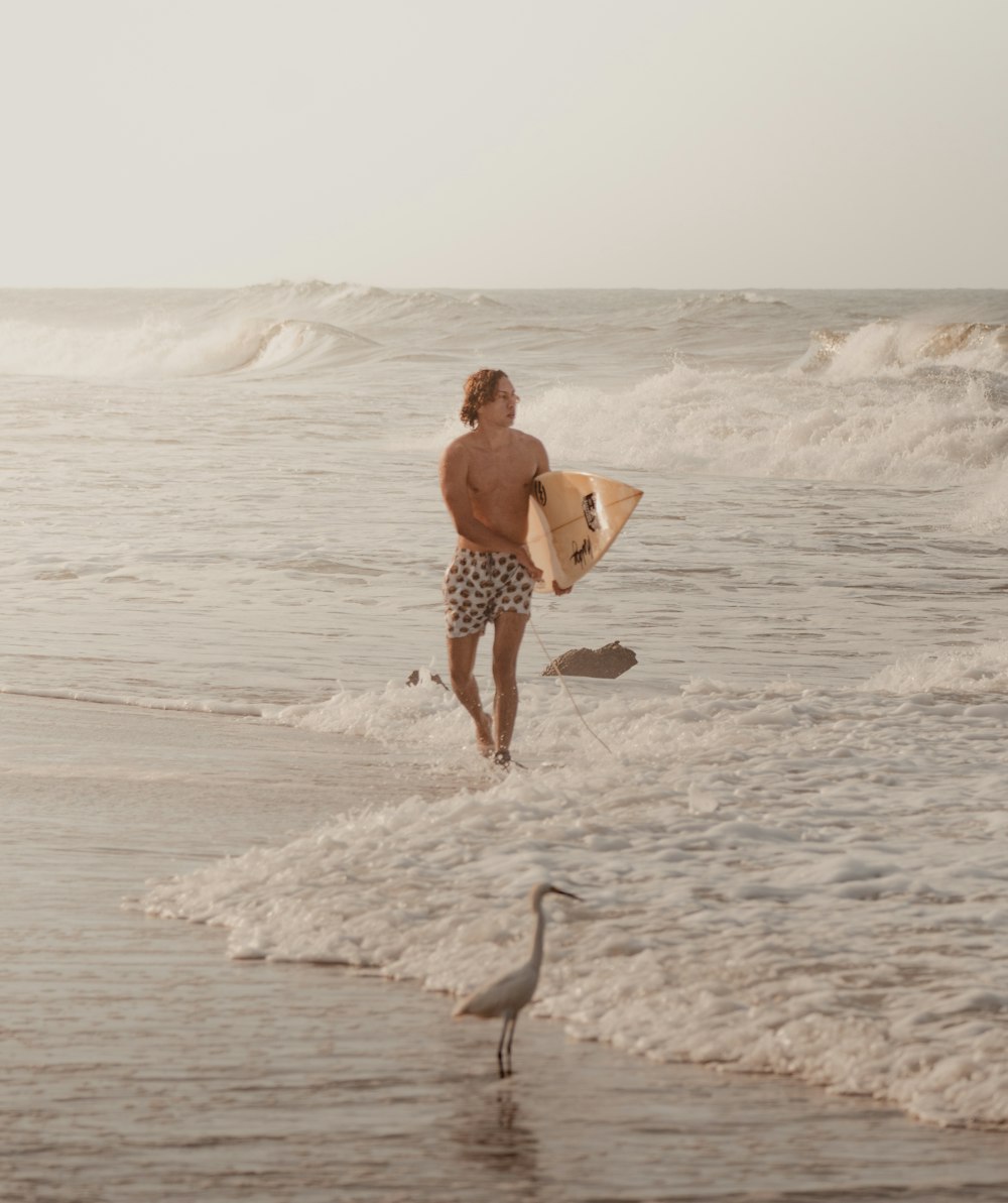 a man holding a surfboard walking into the ocean