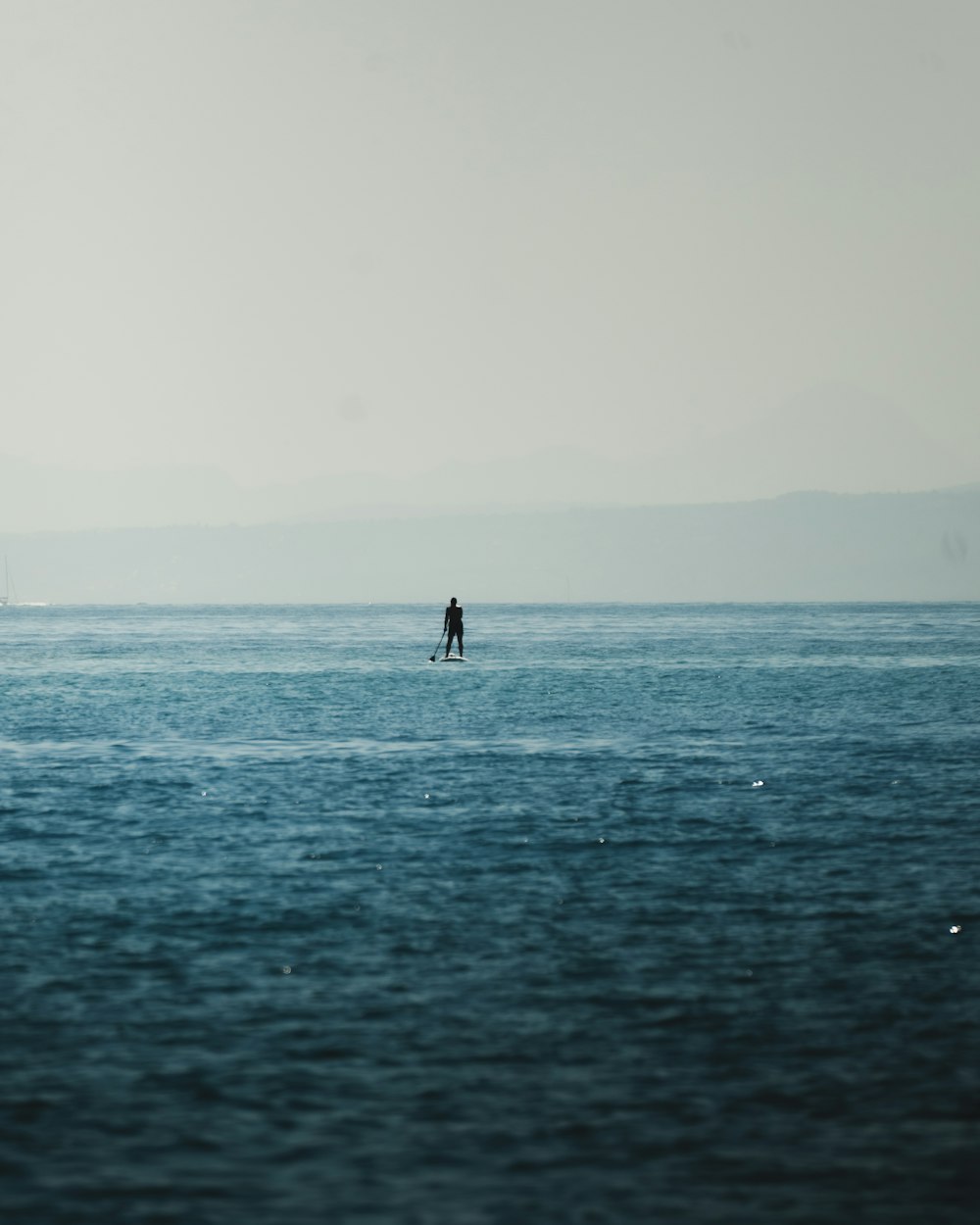 a person standing on a surfboard in the middle of the ocean