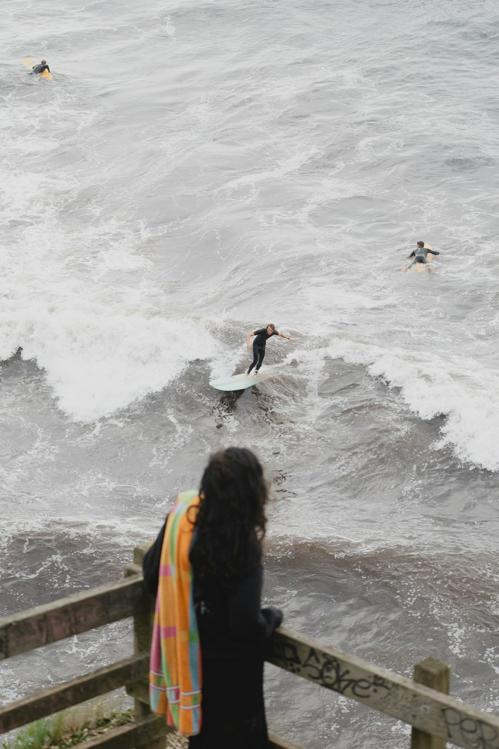 a woman watching surfers ride a wave in the ocean