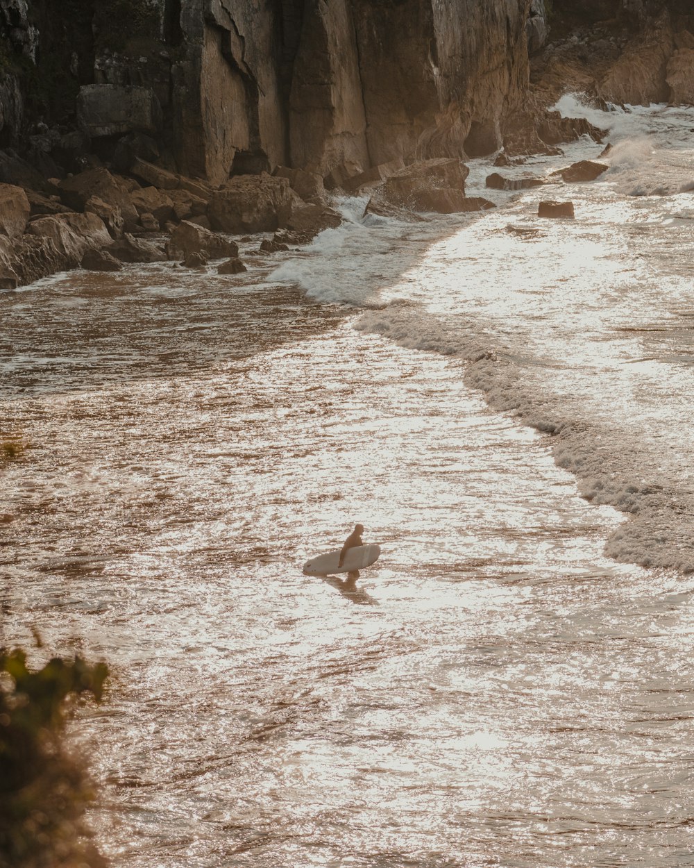 Un surfeur marche dans l’eau avec sa planche de surf