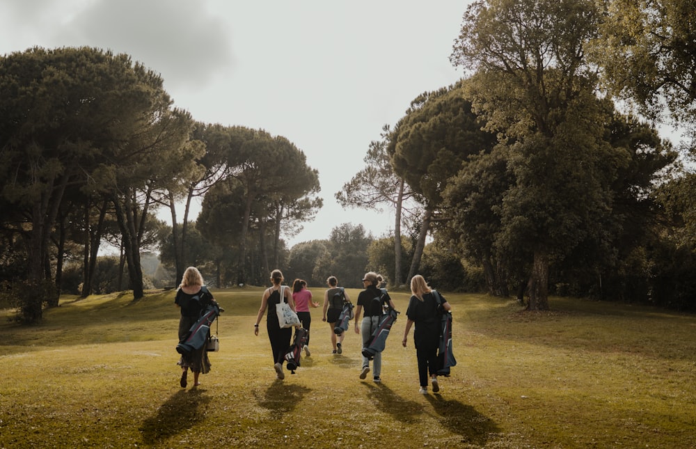 a group of people walking across a lush green field