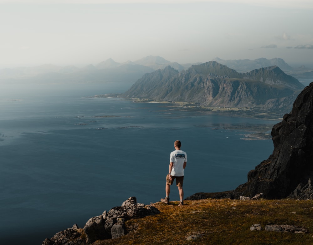 a man standing on top of a mountain next to a body of water