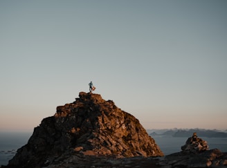 A superhero figure standing triumphantly on a mountain peak.