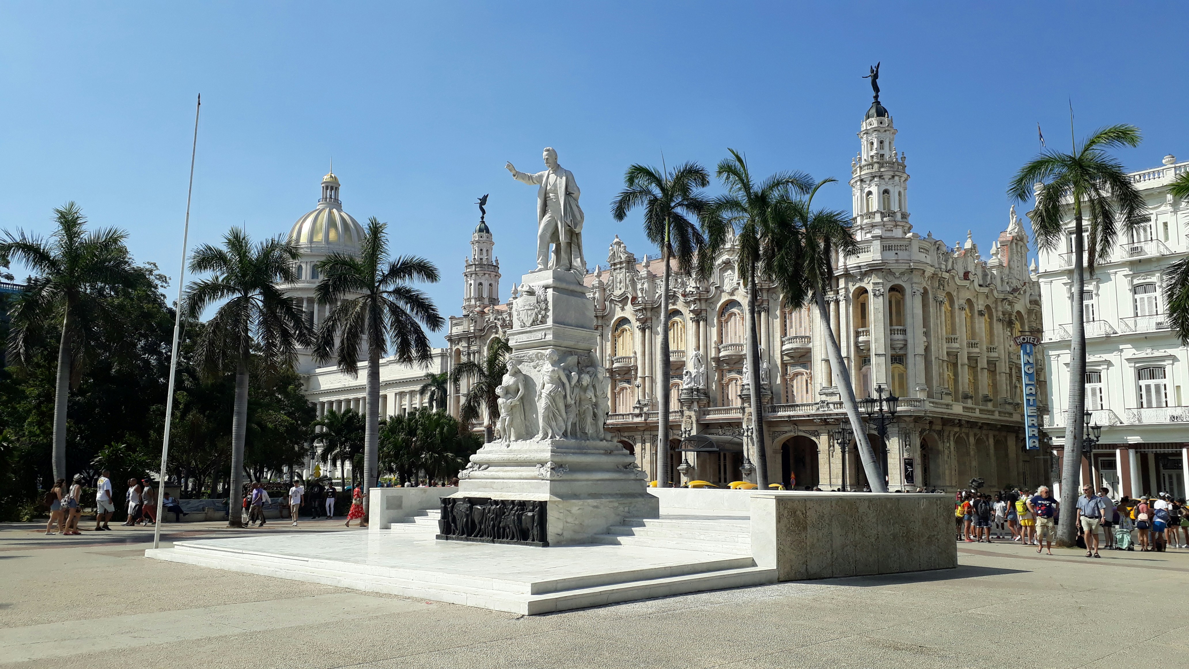 a statue in front of a building with palm trees