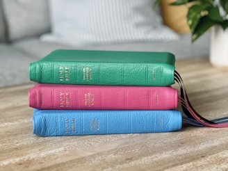 a stack of three books sitting on top of a wooden table