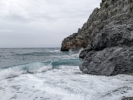 A serene coastal view from the sky, showing waves gently crashing on rocky shores