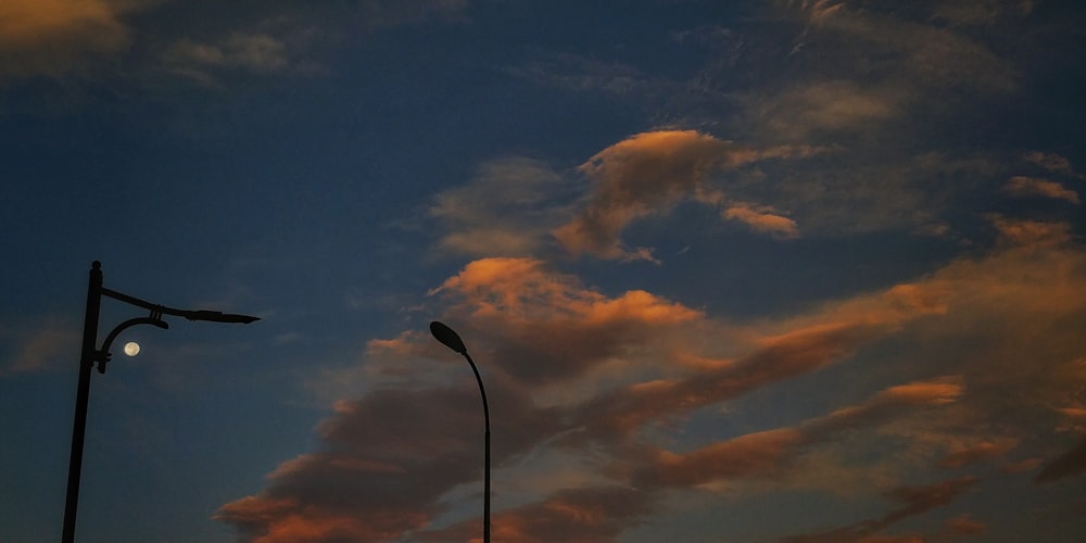 a street light and a street light in front of a cloudy sky