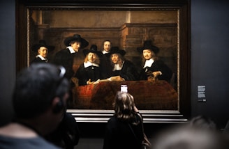 a group of people standing in front of a painting