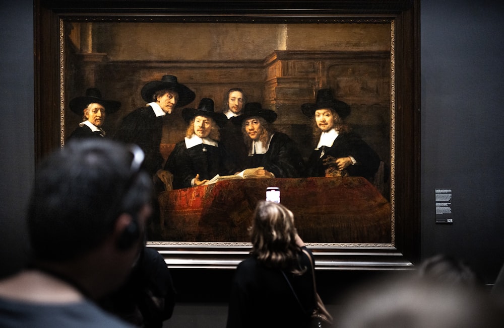 a group of people standing in front of a painting