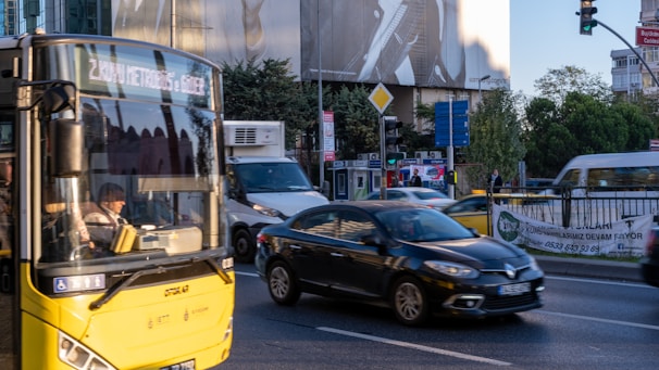 A busy city street with a variety of vehicles displaying colorful advertising wraps and stickers.