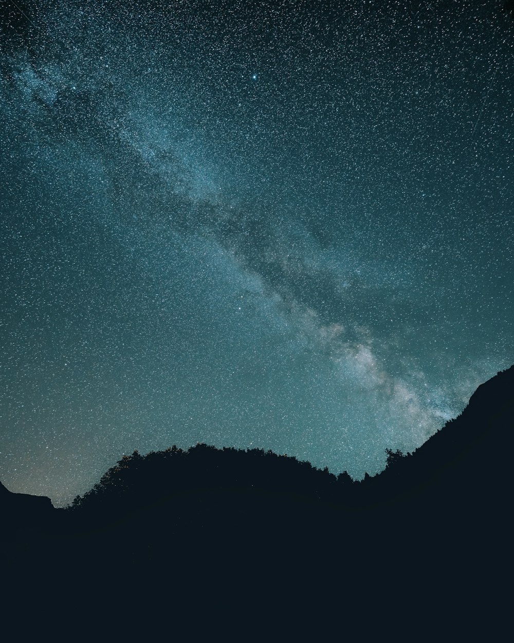 the night sky with stars above a mountain