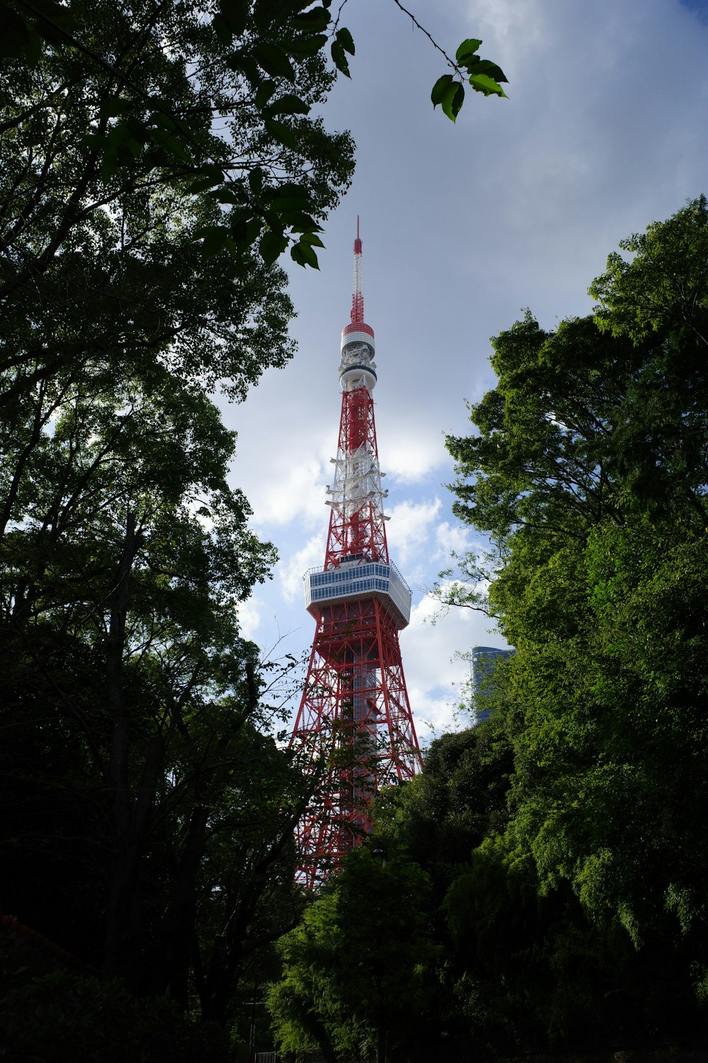 a red and white tower in the middle of trees