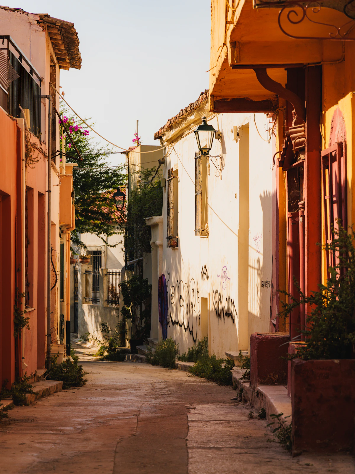 A narrow, colourful lane with plants and a lamp in Athens' Plaka district