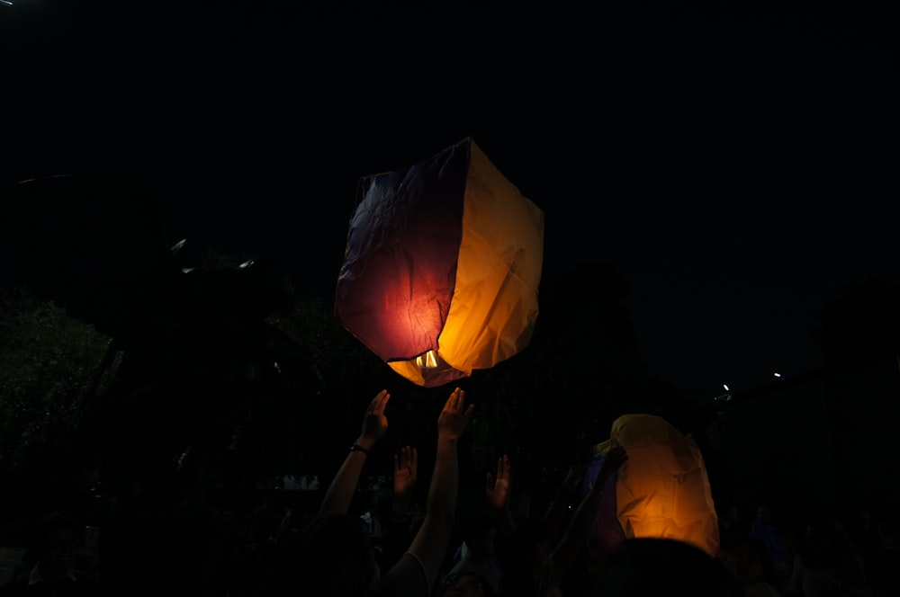 a group of people holding up lanterns in the dark