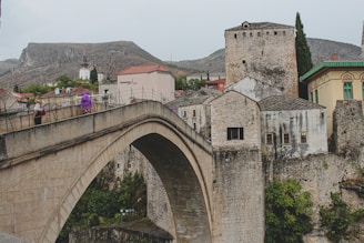 A runner crossing a historic stone bridge with ancient architecture in the background.