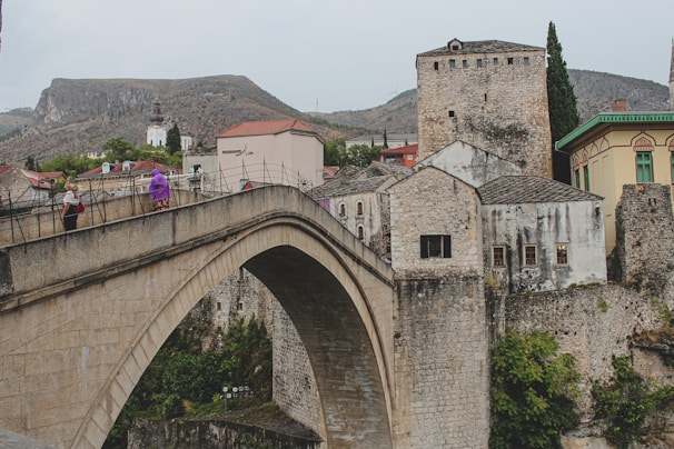 A runner crossing a historic stone bridge with ancient architecture in the background.