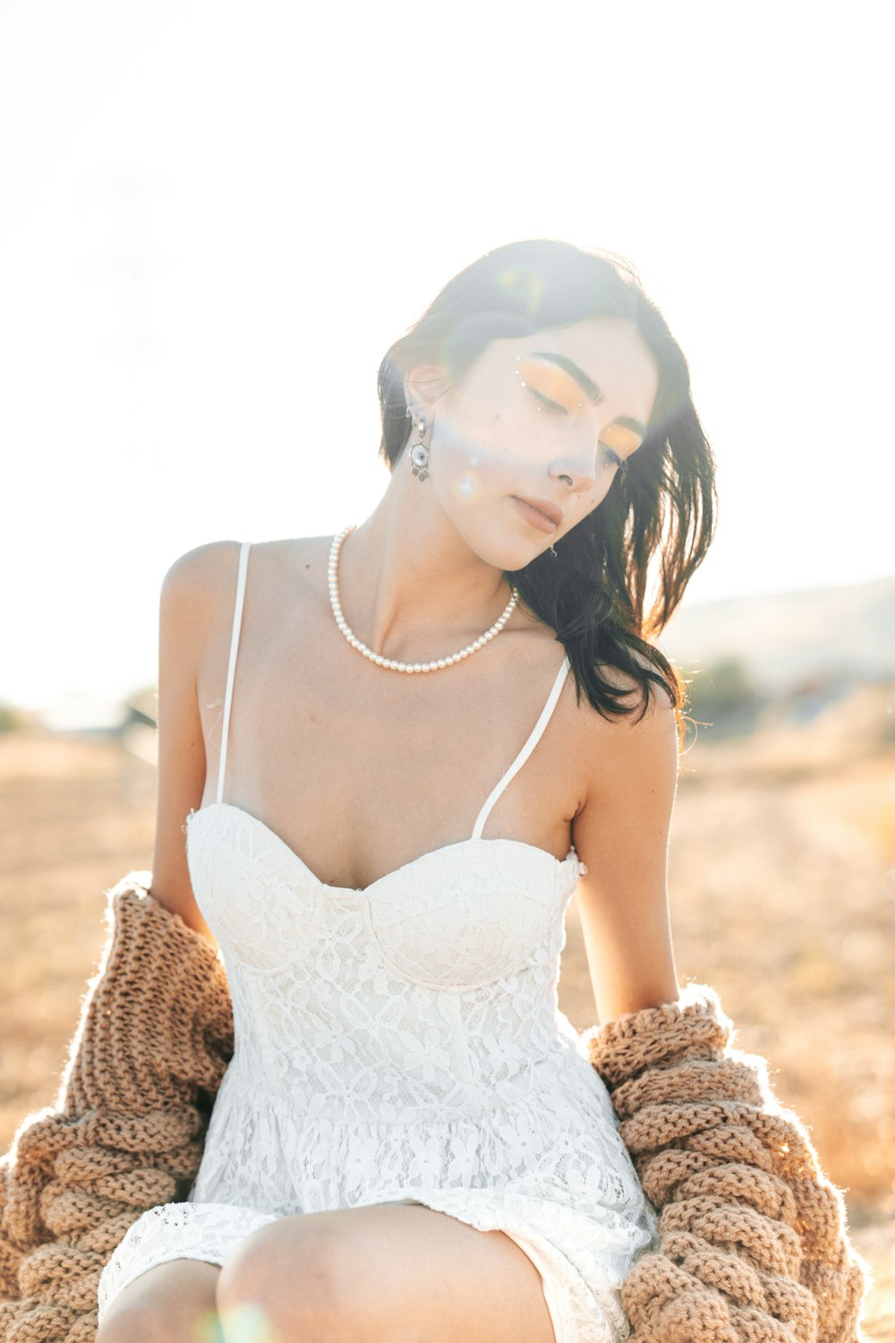 a woman in a white dress sitting on the ground