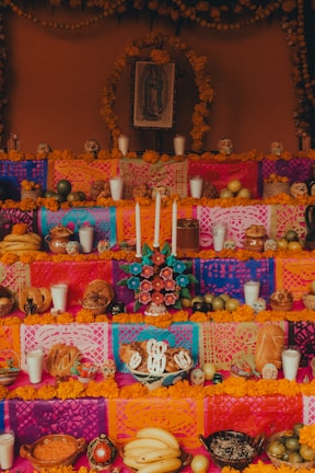A colorful altar with various candles lit, framed by sacred symbols and flowers.