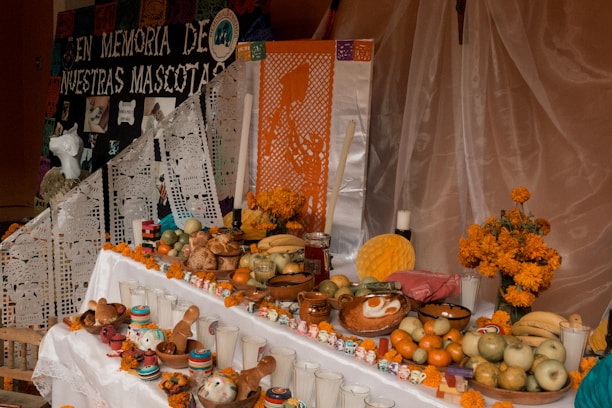 A dimly lit altar decorated with candles, marigold flowers, and Death Day Candy wrappers scattered around.