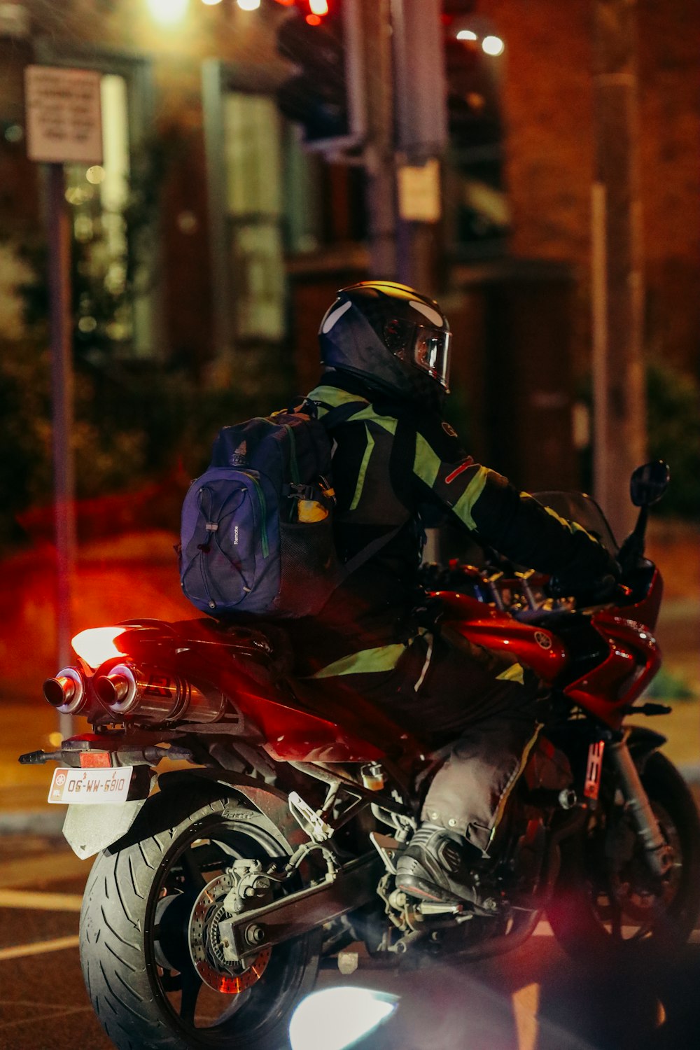 a man riding a red motorcycle down a street