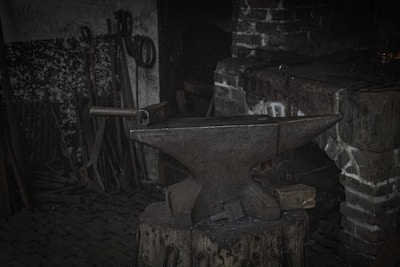 Anvil and tools laid out on a wooden table near Scottish castle ruins.