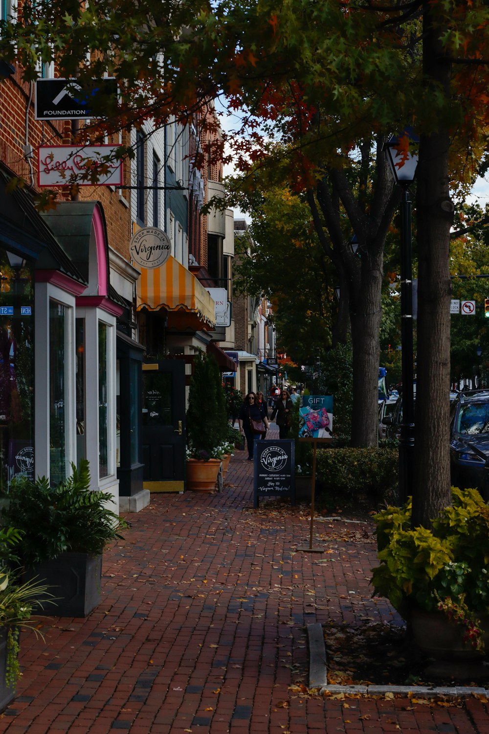 a brick sidewalk with shops and people walking on it