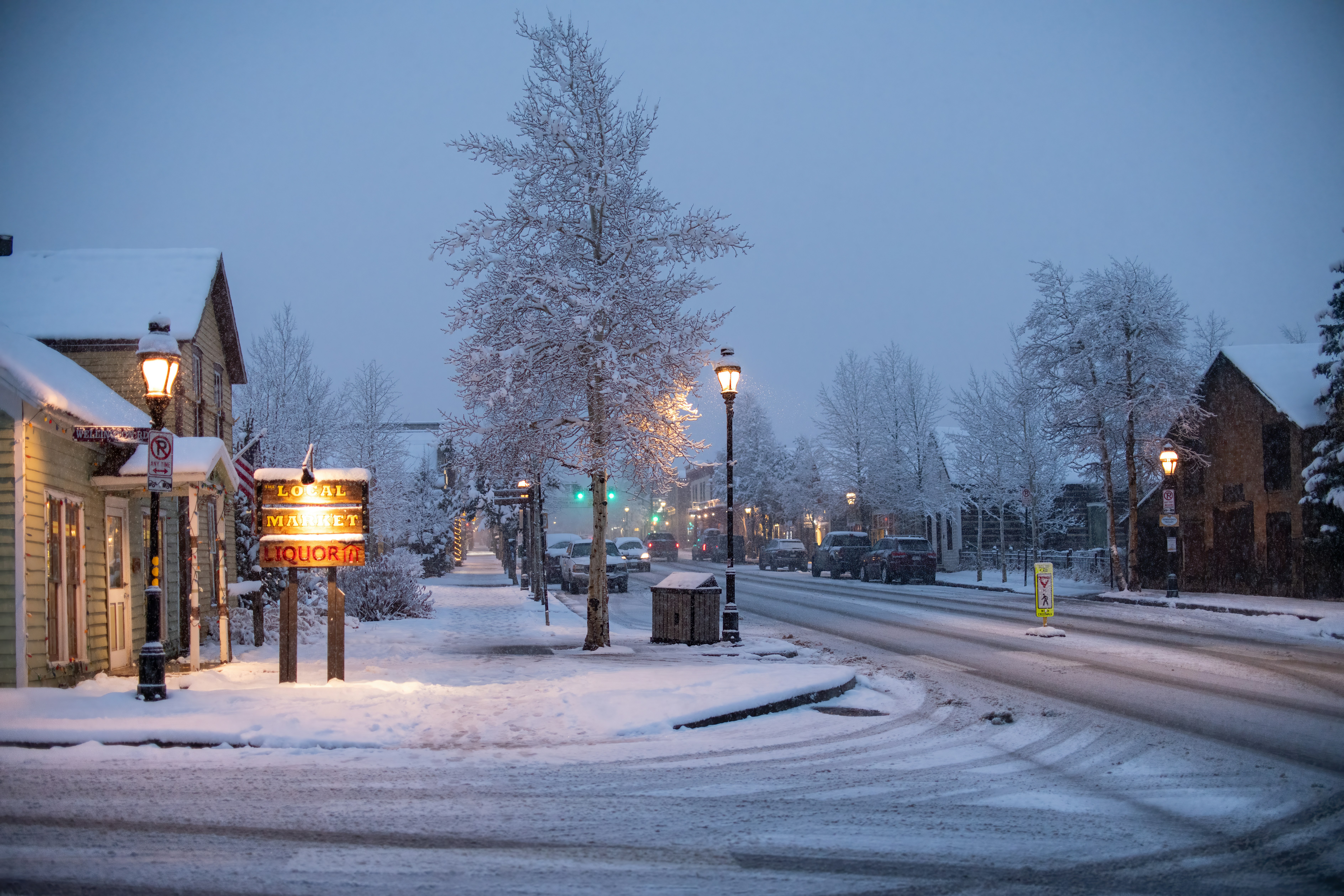 snowy main street of Crested Butte CO with shops adorned with holiday lights