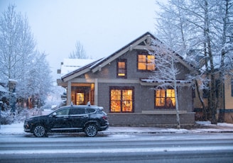 a car parked in front of a house on a snowy day