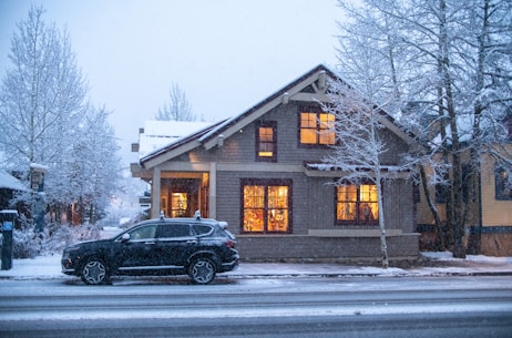 a car parked in front of a house on a snowy day