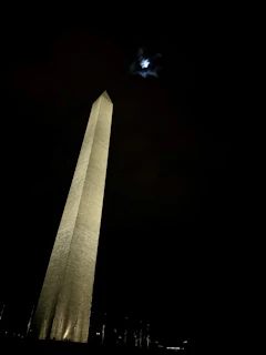An ancient, rune-etched monolith standing solitary beneath a twilight sky over the city of Vorjuun.