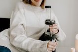 User holding a portable hydrogen inhaler device with a smile in a cozy home setting.