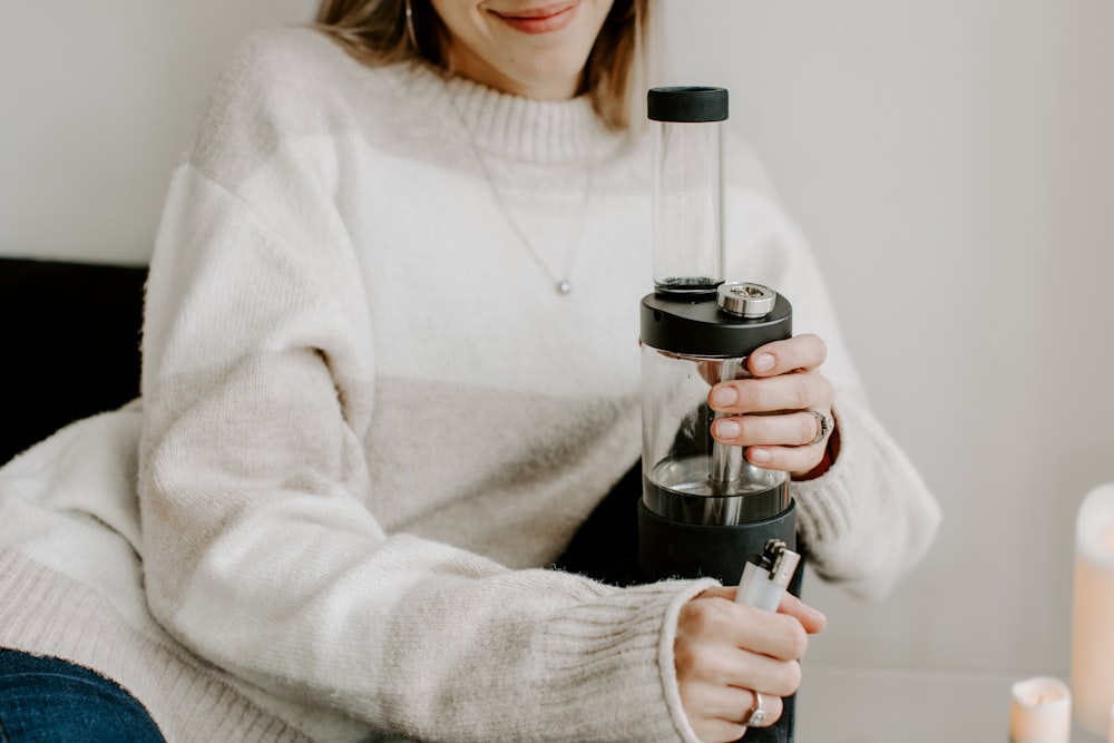 a woman holding a coffee cup and a blender