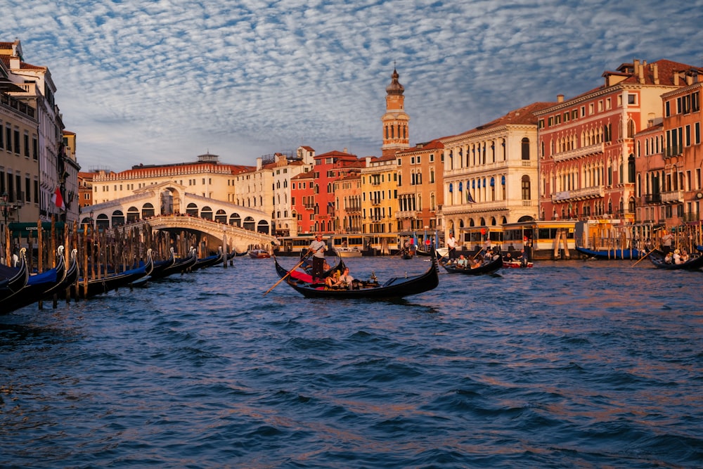 a couple of gondolas floating down a river next to tall buildings