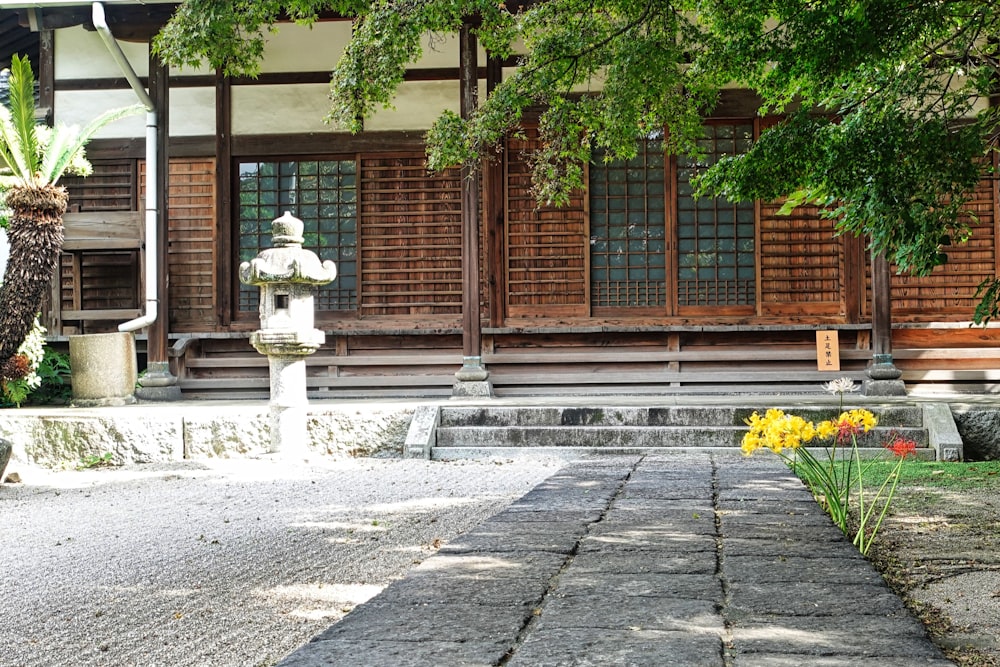 a stone walkway leading to a building with wooden shutters