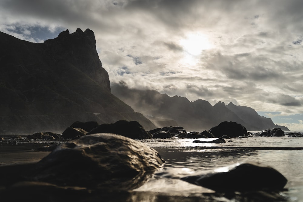 a rocky beach with a mountain in the background