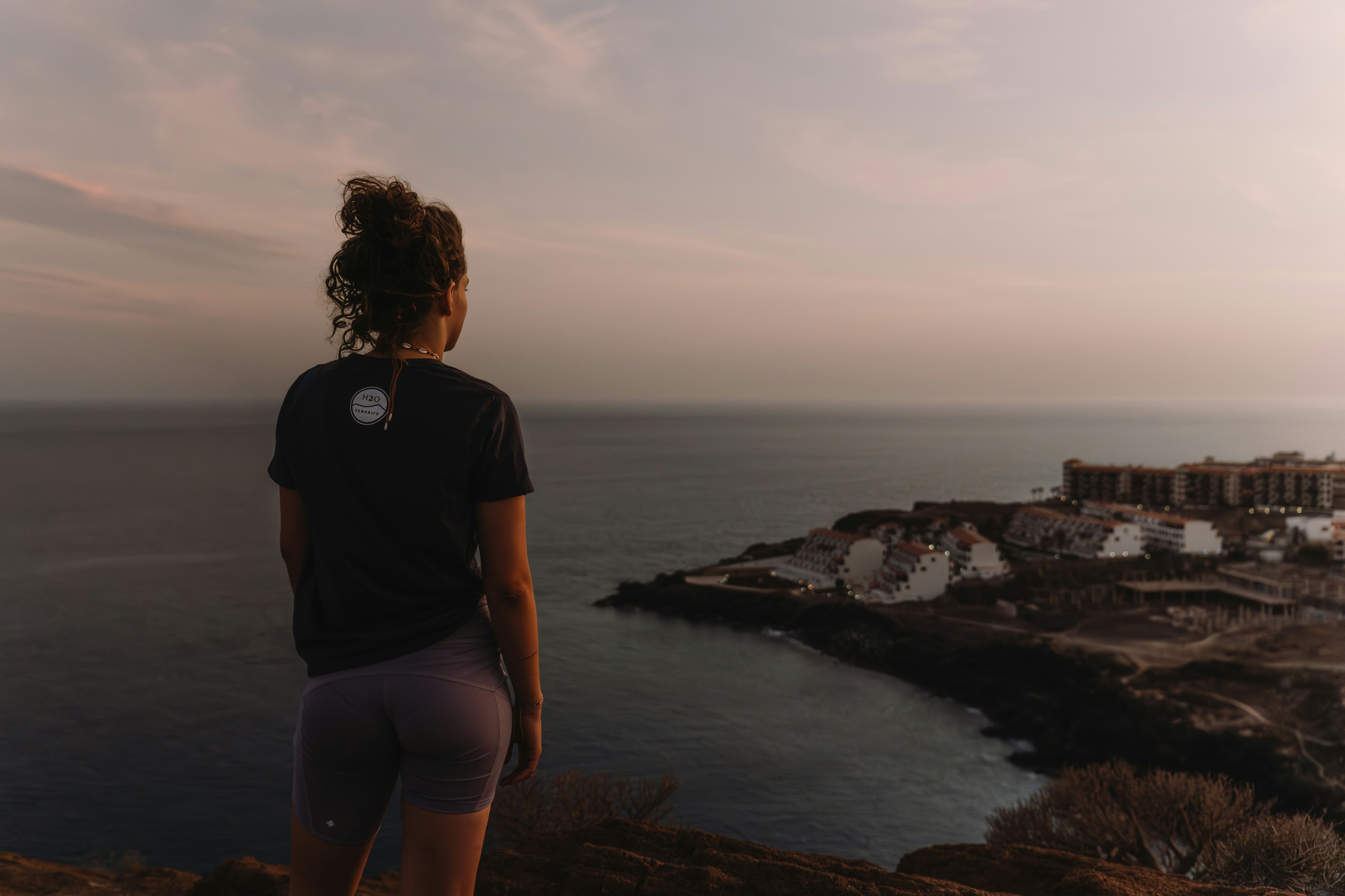a woman standing on top of a hill next to the ocean