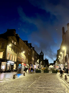 A serene view of a cobblestone street in a historic European city at dusk, with warm lights glowing from boutique shops.