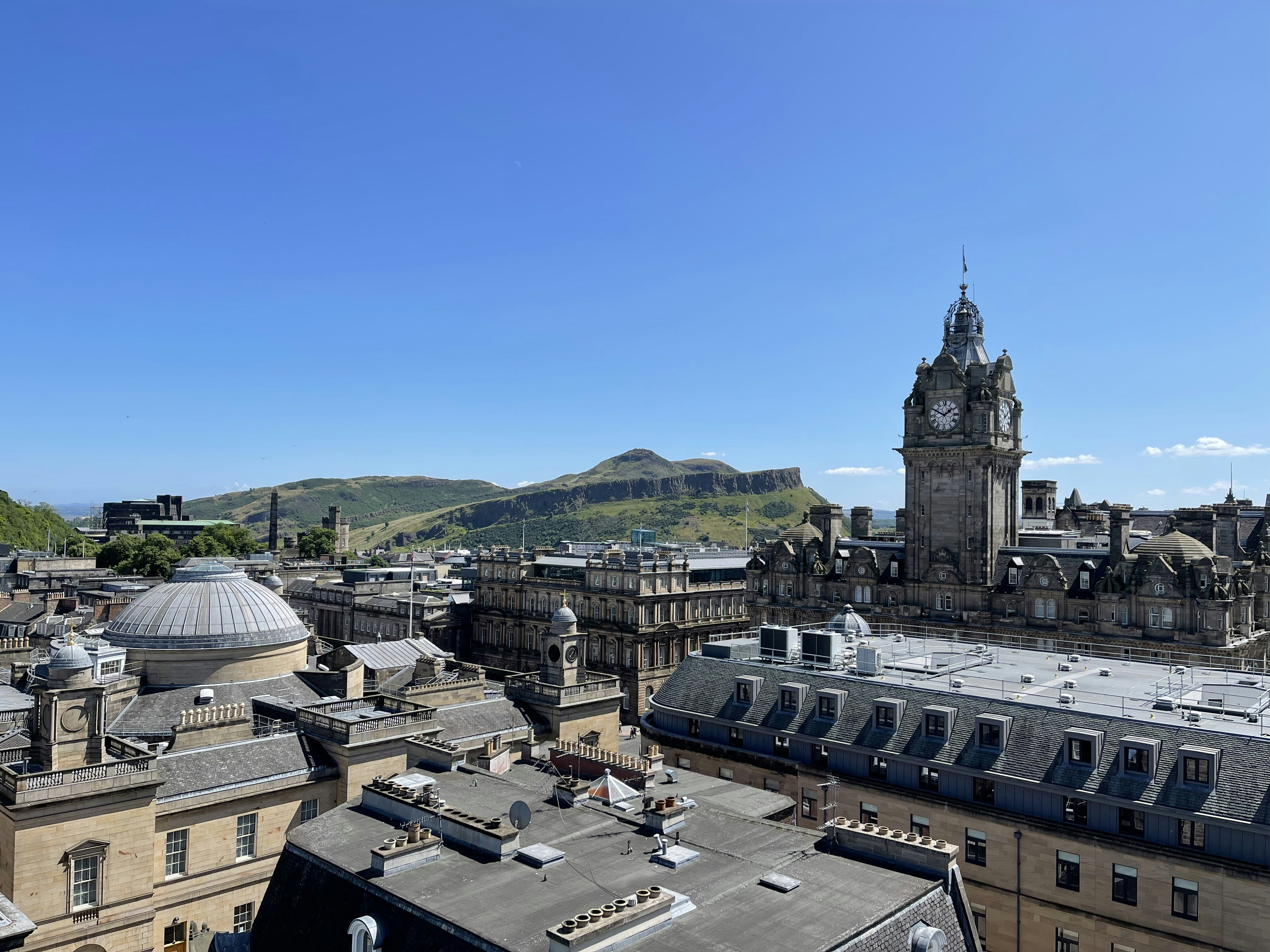 a clock tower towering over a city with mountains in the background