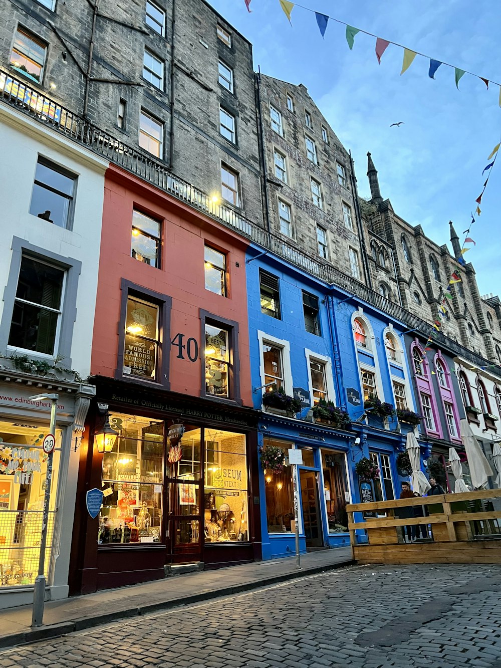 a row of multi - colored buildings on a cobblestone street