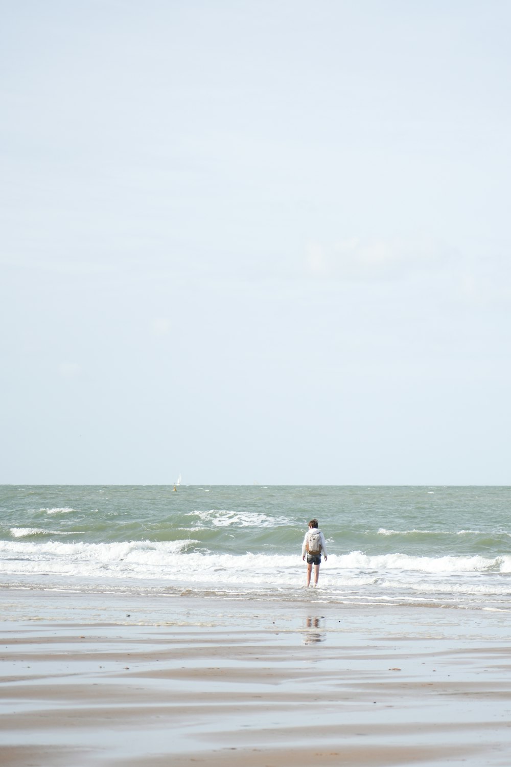 a person standing on a beach flying a kite