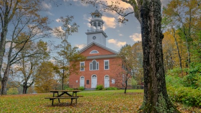Historic Liberty Bell framed by autumn leaves on a sunny day.