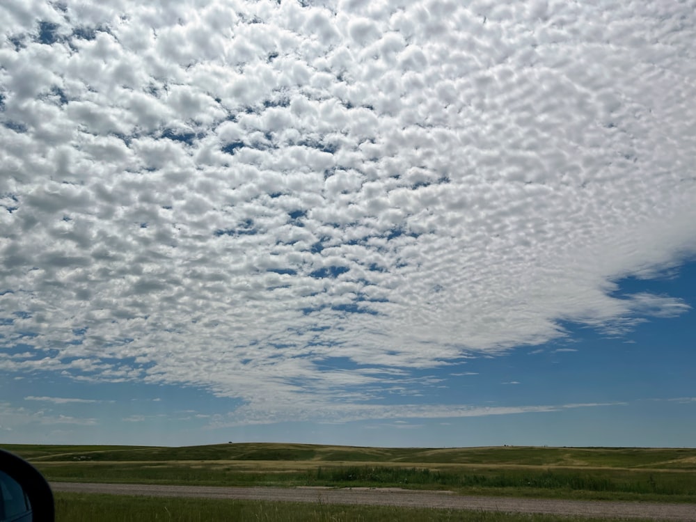 a car driving down a road under a cloudy blue sky