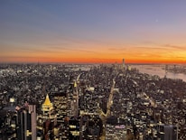 A stunning city view from a high-rise apartment balcony at sunset.