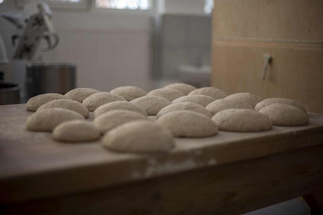 a wooden table topped with lots of doughnuts, Sourdough breads before baking laying on table in artisan bakery.