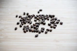 Artistic shot of coffee beans scattered over rustic wooden table with gentle golden rays illuminating them.