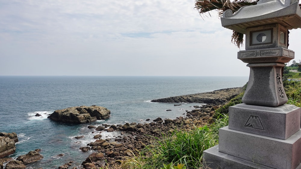 a stone lantern sitting on the side of a cliff next to the ocean
