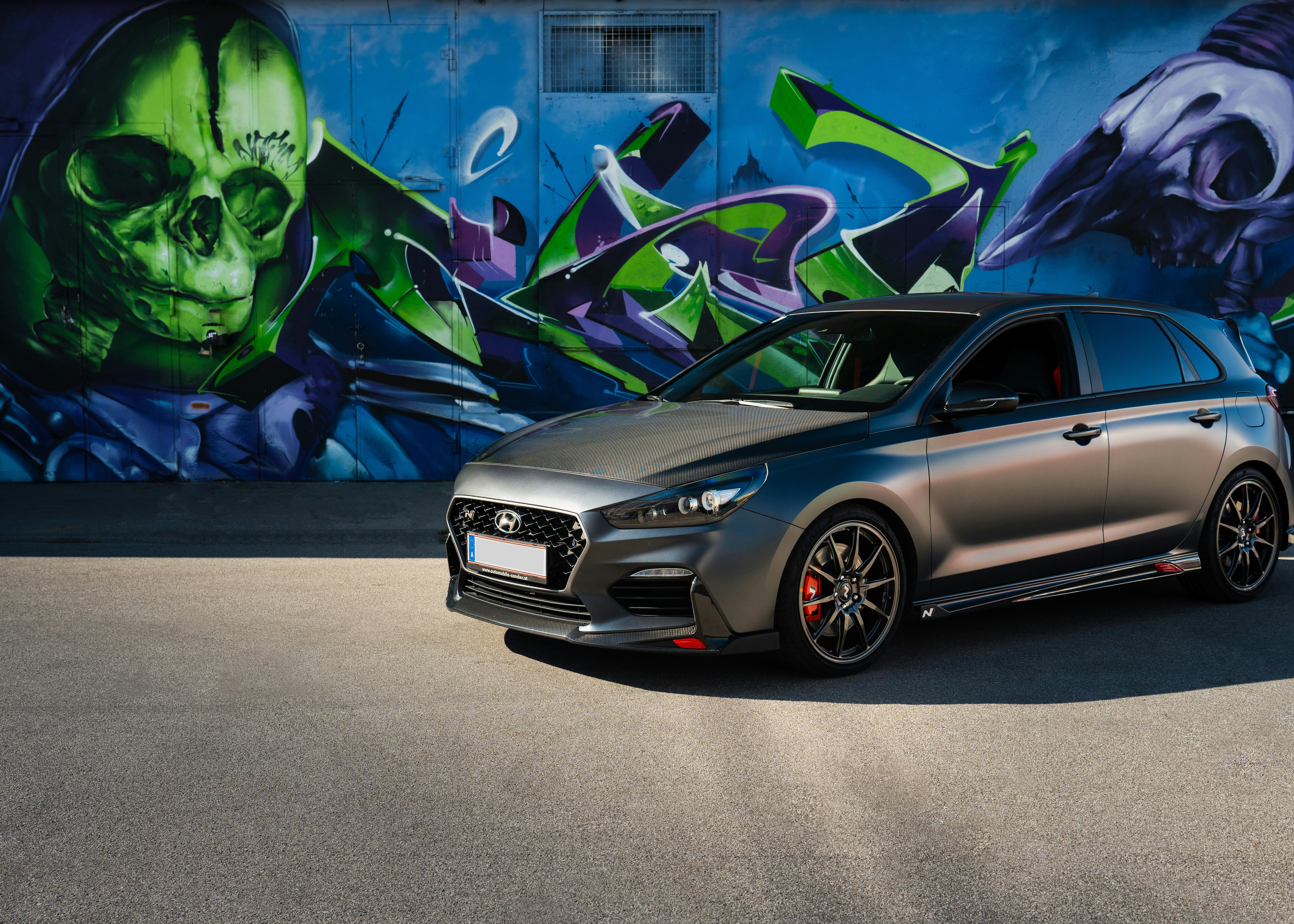 a silver car parked in front of a graffiti covered wall