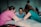 Three individuals are sitting around a table, deeply engaged in conversation. The central figure has a contemplative expression, while the other two, positioned on either side, appear supportive and attentive.
